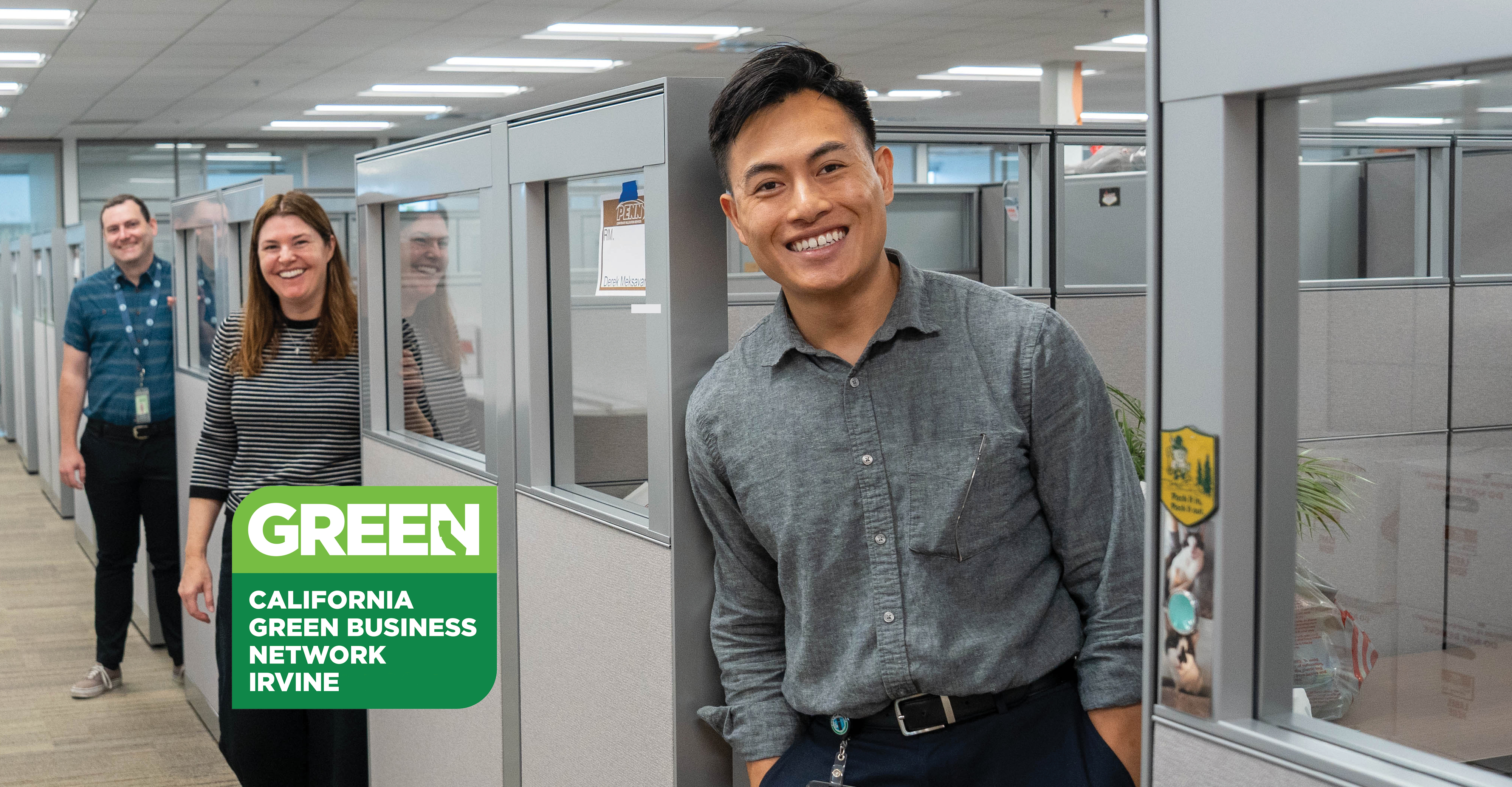 Smiling man, two coworkers in office. Green California Green Business Network logo.