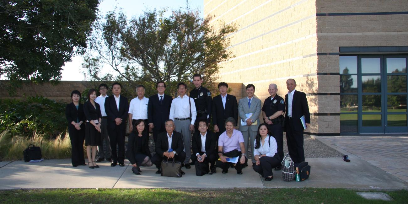 Group of professionals, some in uniform, posing outdoors in front of a modern building.