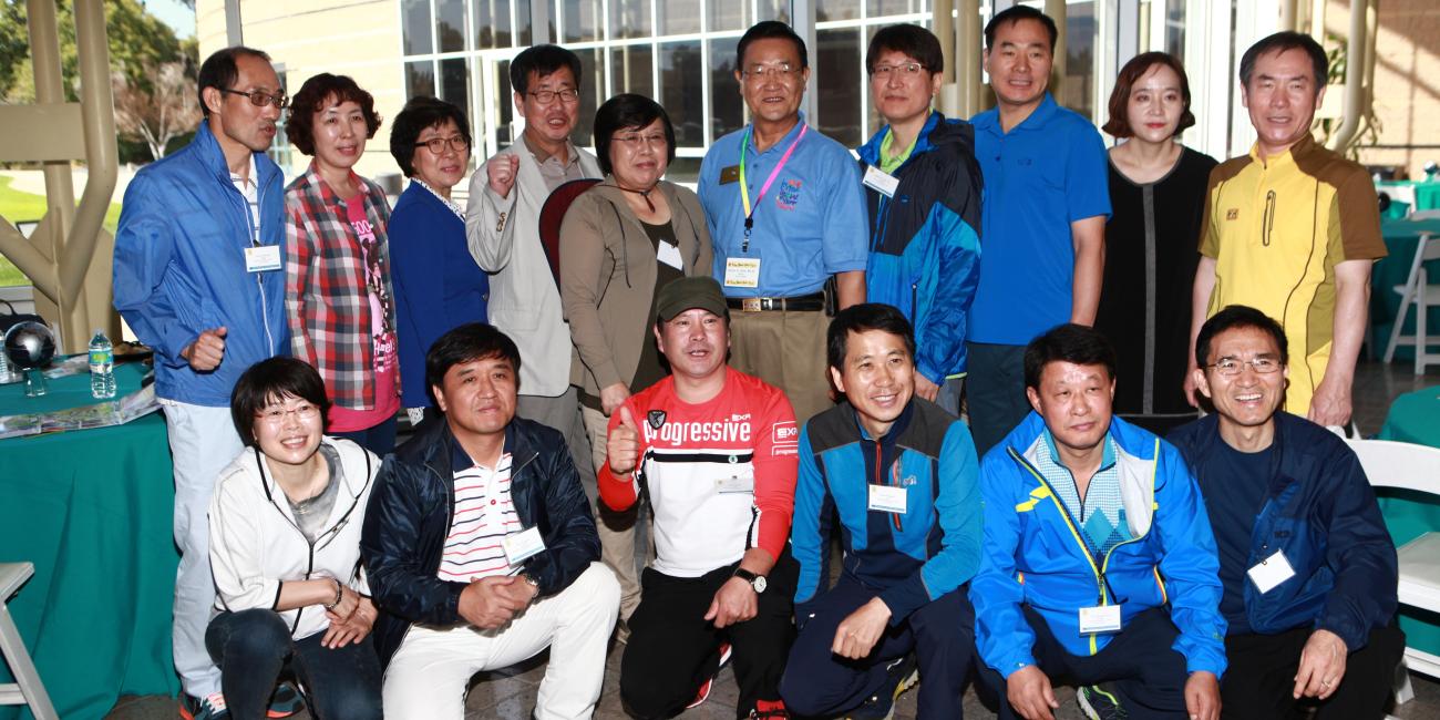 Photograph of smiling adults, some standing, some crouching, at an outdoor event.