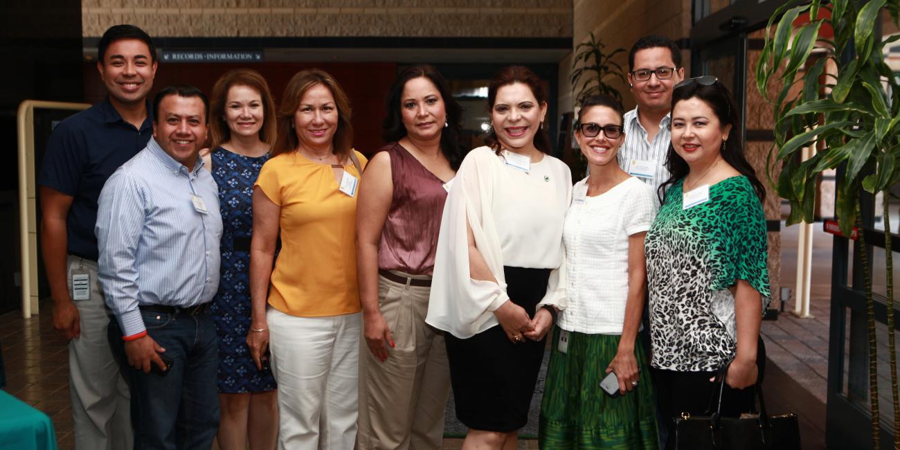 Smiling group of ten adults, men and women, posing indoors.