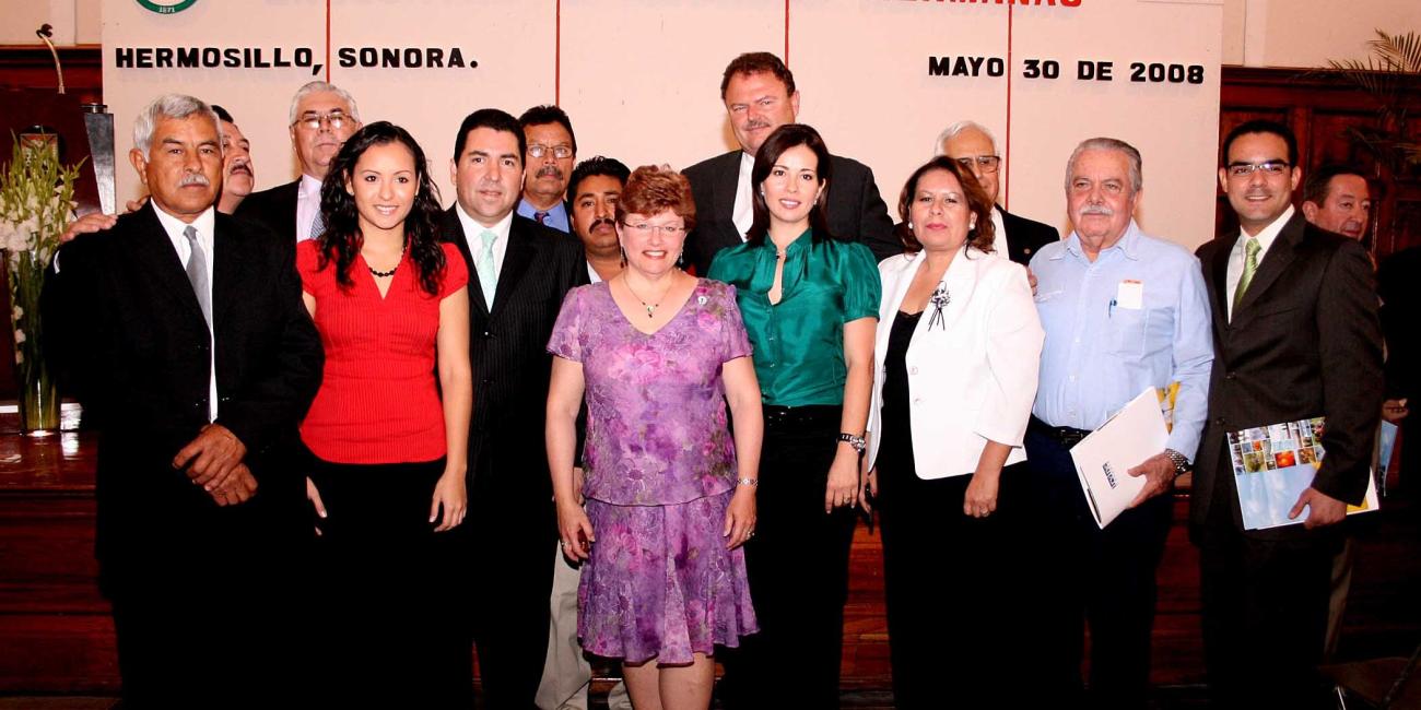 Smiling group of adults, men and women, posing indoors.