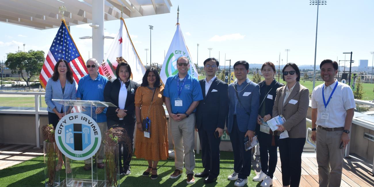 Photograph of smiling adults posing in front of a podium at a sports park