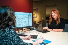Two women at the development counter, one smiling at the other.