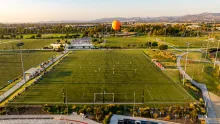 Golden hour aerial view of the Great Park Sports Complex with a soccer game underway and the Great Park Balloon.