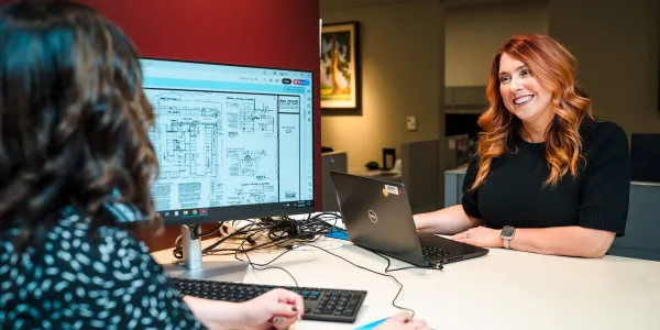 Two women at the development counter, one smiling at the other.