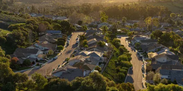 Aerial view of a suburban neighborhood nestled in a valley with a golden sunset.