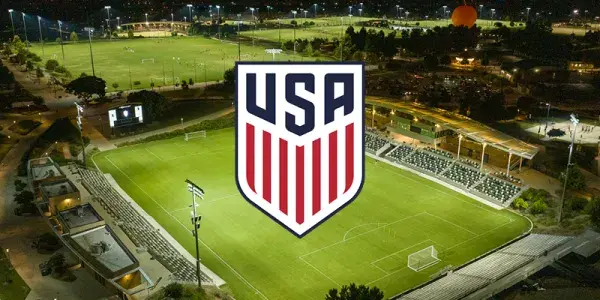 USA soccer logo over a brightly lit stadium at night, with city lights in background.