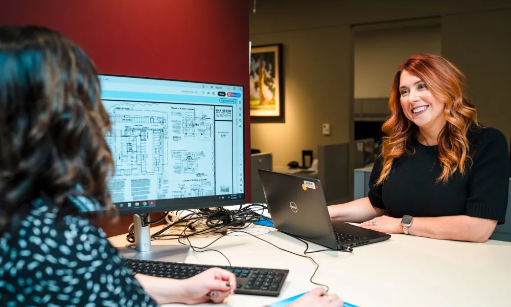 Two women at the development counter, one smiling at the other.