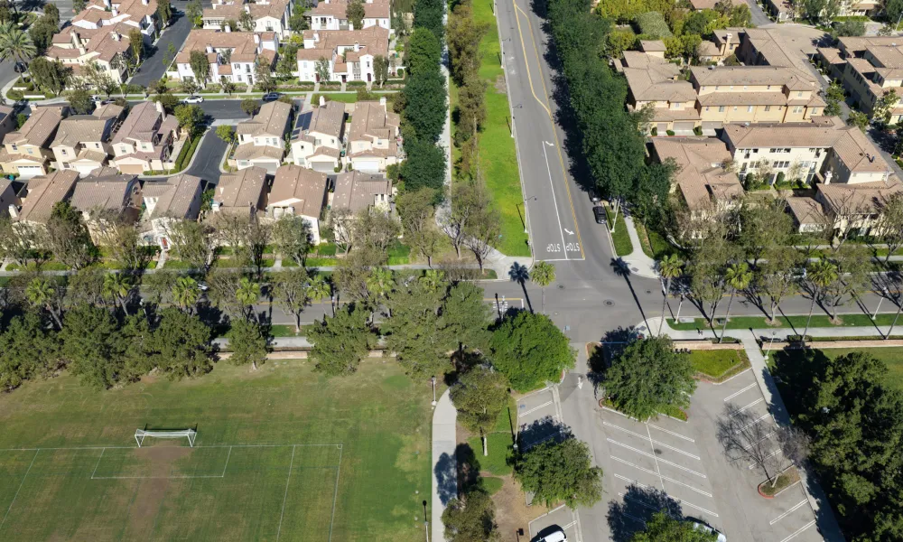 Aerial view of a planned community with houses, roads, a soccer field, and parking.
