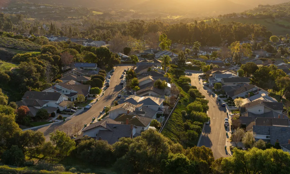 Aerial view of a suburban neighborhood nestled in a valley with a golden sunset.