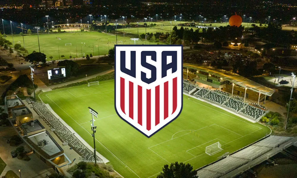 USA soccer logo over a brightly lit stadium at night, with city lights in background.