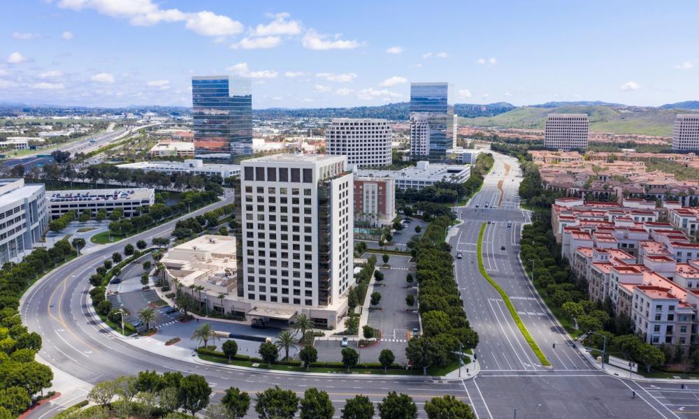 Several tall buildings surrounded by roads, trees, and houses