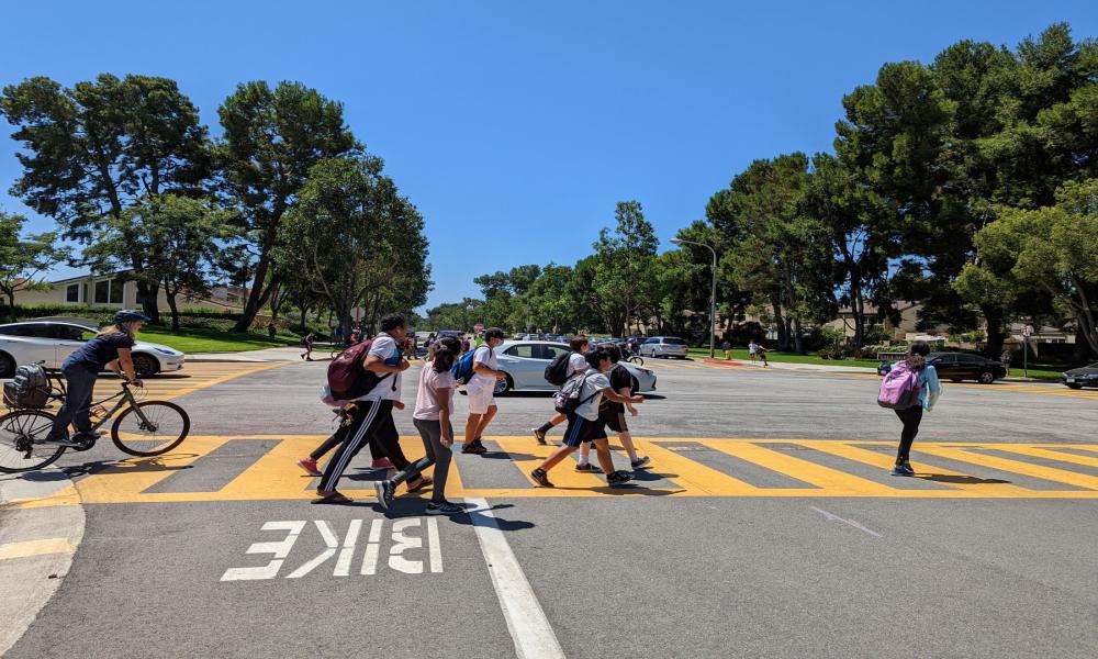 kids walking and bike riding in a crosswalk 