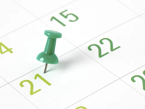 Green thumbtack marking day 21 on a calendar.