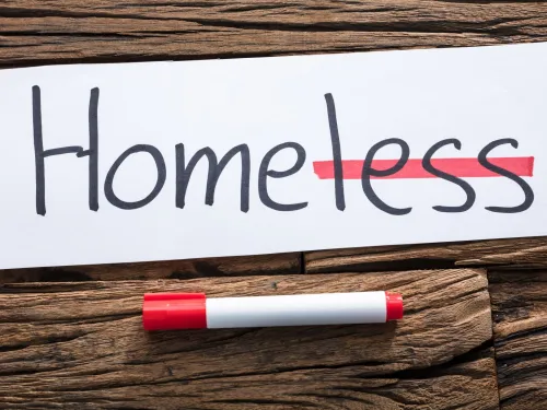 Photograph: "Homeless" written on paper, "less" struck out in red, implying "Home."