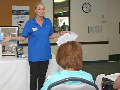 Woman with a blue polo shirt presenting to an audience