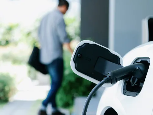 White electric car charging, man walks away from it.