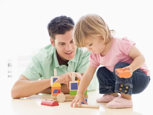 child playing with toys alongside male figure