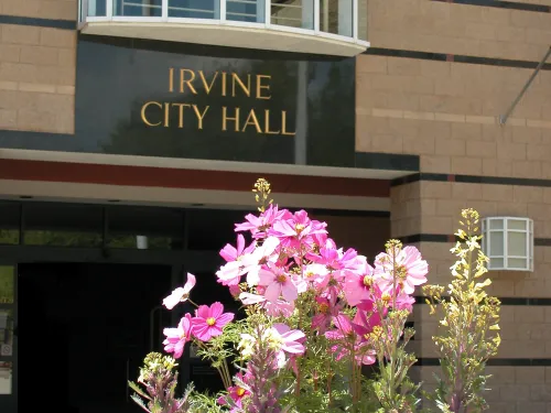 Irvine City Hall entrance with pink and purple flowers in the foreground. Photograph.