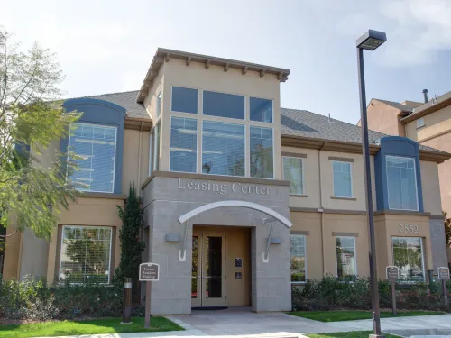 Tan commercial building with stone entrance, large windows, and blue architectural details.