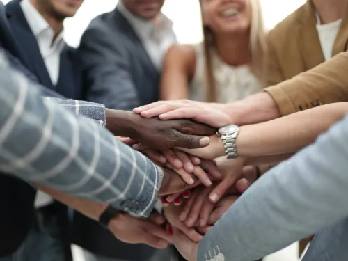 Photograph: Diverse hands stacked together, symbolizing teamwork.